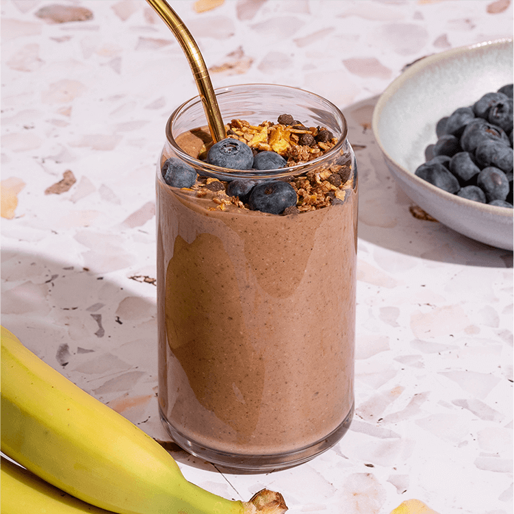 Schoko Protein Shake mit Bananen und Blaubeeren daneben