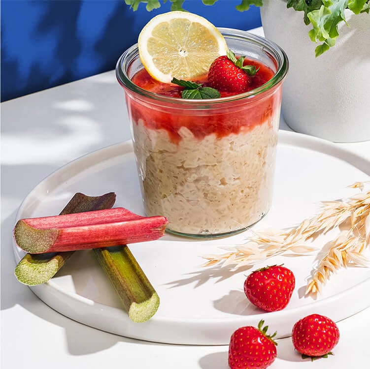 Milchreis mit Rhabarber-Erdbeer-Kompott im Glas und mit einer Zitronenscheibe und ganzen Erdbeeren dekoriert