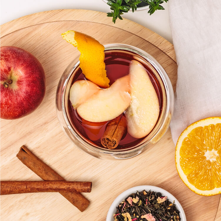 Winterpunsch im Glas mit Orangenschale und Apfelstücken dekoriert