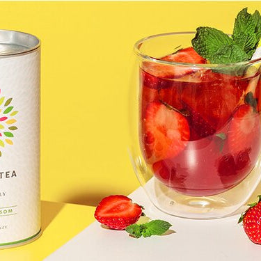 Erdbeer-Minz Eistee in einem Glas mit Teedose daneben