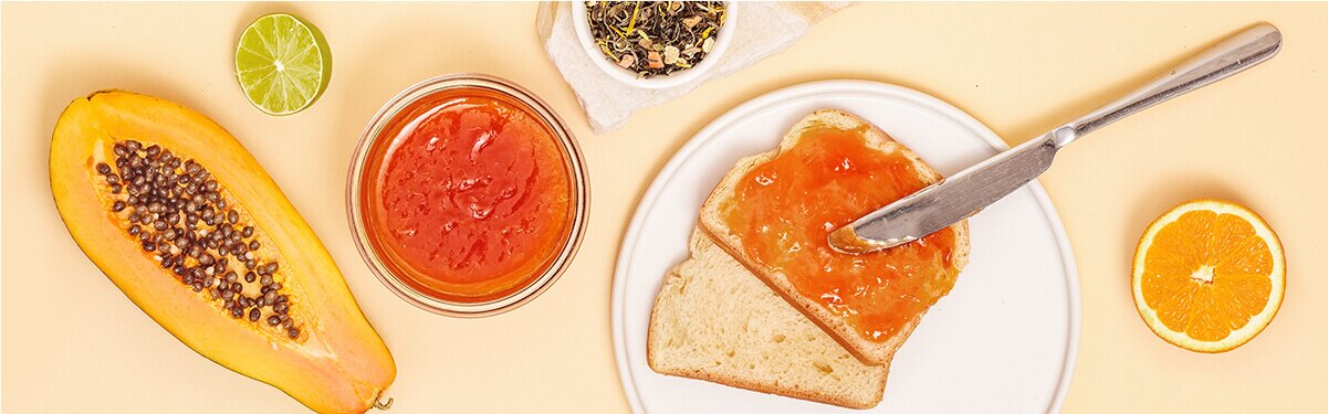 Papaya Orangen Marmelade auf einem Brot mit einer halben Papaya daneben