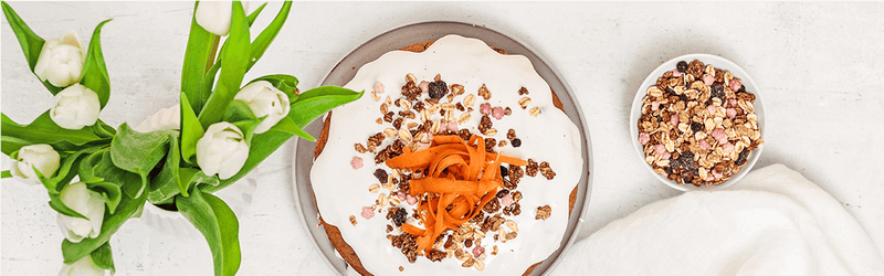Naked Carrot Cake auf einem Teller, mit geraspelter Möhre dekoriert