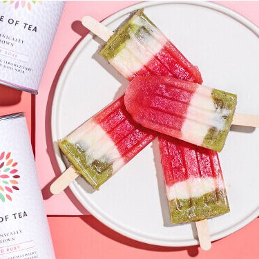 Popsicle-Eis mit Wassermelone auf einem Teller mit Teedosen daneben