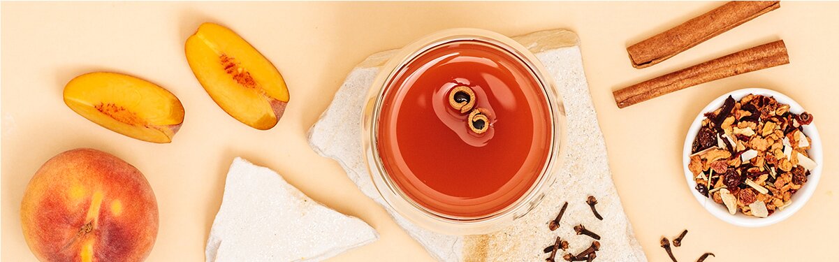 Pfirsich Punsch mit Zimtstangen und Pfirsiche daneben