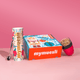 Das mymuesli Geschenkset, bestehend aus Bio Baked Apple Cookie Crunchy, Müsli To-go Becher in magenta / pink und einem silbernen mymuesli Löffel. Verpackt in einer weihnachtlichen Geschenkbox. 