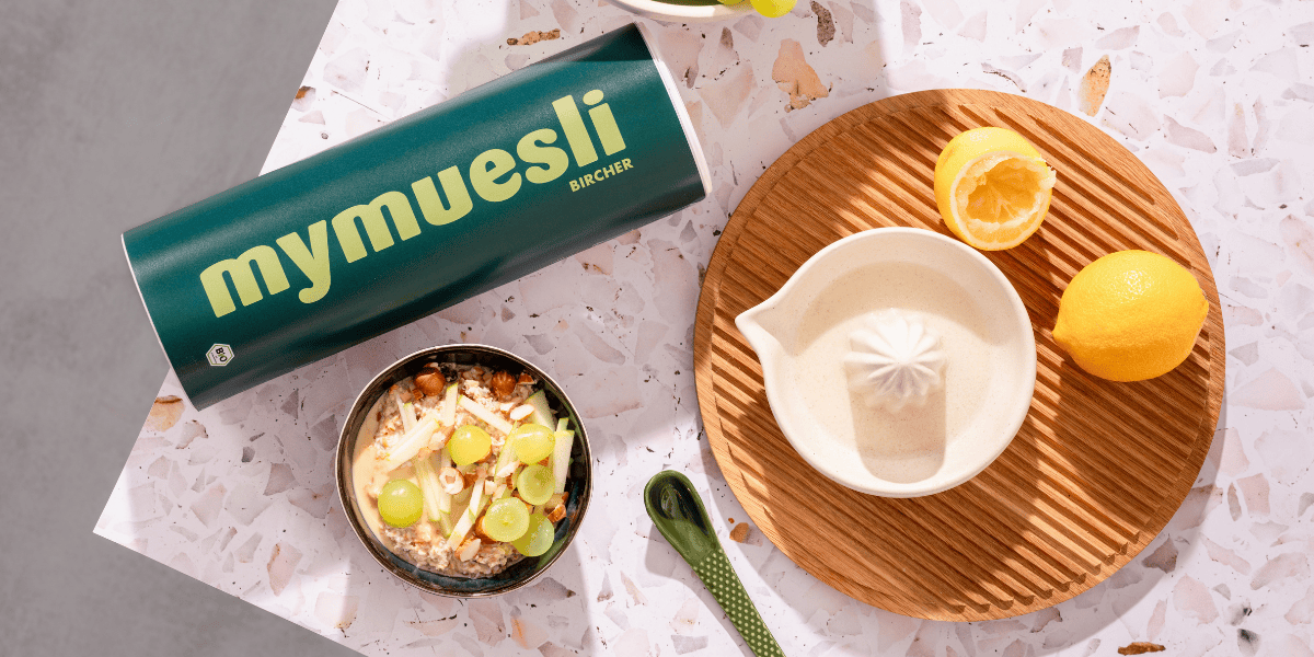 Das mymuesli Bio Berry Bircher Müsli, angerichtet mit frischen Äpfeln und Weintrauben auf einem Küchenthresen.