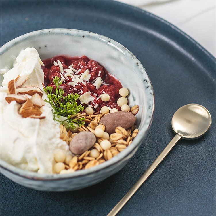 Winterliches Quark-Himbeerkompott mit Adventsmüsli auf einem Teller