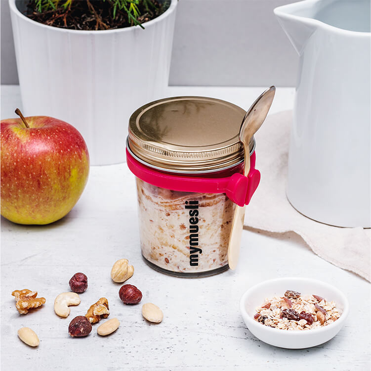Bircher Müsli in einem Glas mit einem Apfel daneben
