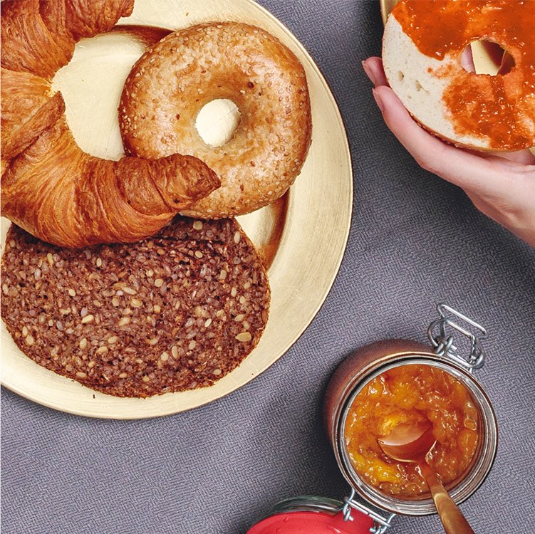 Ein Teller mit Croissant, Bagel und Brot und Earl Grey Marmelade daneben