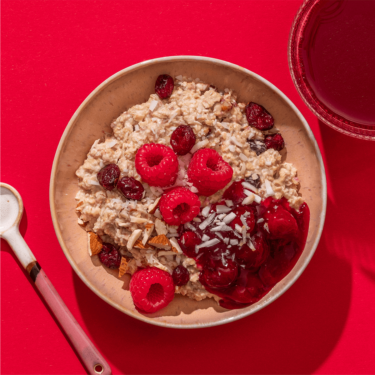 Detailansicht eines zubereiteten Porridges mit roten Beeren und Kokosraspeln.