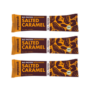 Drei übereinander gestapelte "Salted Caramel" Bio-Müsliriegel in gelb-brauner Verpackung auf schwarzem Hintergrund.