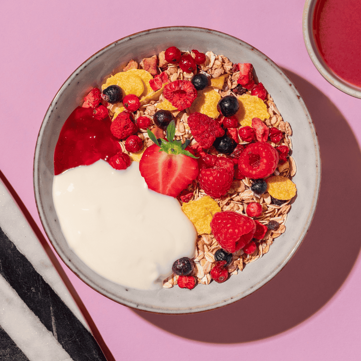 mymuesli Bio Berry Müsli mit Himbeeren, Erdbeeren und Blaubeeren in Schüssel mit frischen Beeren und Joghurt