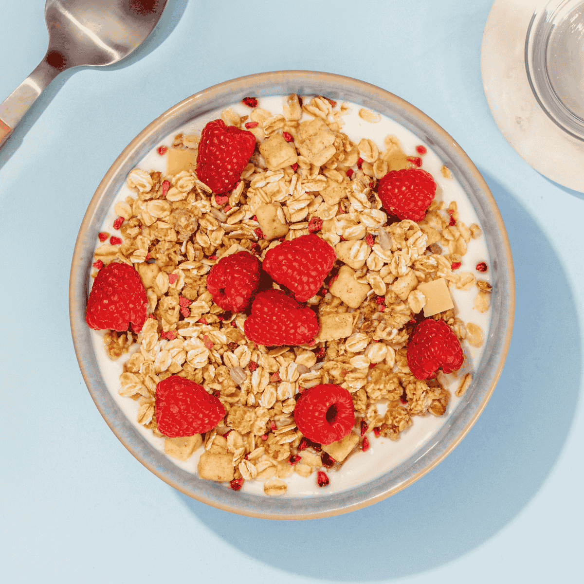mymuesli Bio Low Sugar Yoghurt Raspberry Crunch in Schale mit Joghurt und frischen Himbeeren