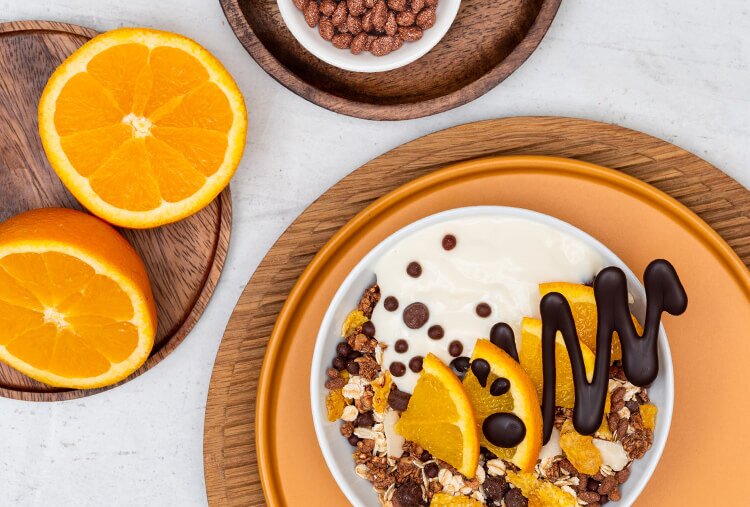 Mueslischale mit Joghurt, Schokolade und Orangenscheiben